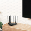 Porodo Dual Band Portable Wi-Fi Router on a wooden table near a television, showcasing its antennas.